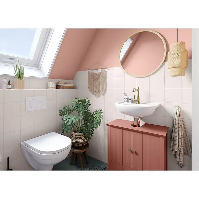 Alpina Wandfarbe Bad & Küche Rosenstaub - Rosa, Matt, 2,5 l - Ein gemütliches kleines Bad mit Dachfenster, hellrosa Wänden, weißen Fliesen, Toilette und Waschbecken mit rötlich-rosa Waschtisch.