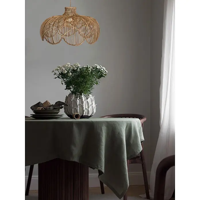 PR Home Pendelleuchte Belle - 15 W, E27 - Hängelampe aus geflochtenem Rattan über einem Esstisch mit grünem Tischtuch und weißen Blumen.