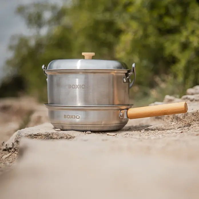 Boxio Topf Set Cookware - Edelstahl - Kochset aus Edelstahl mit Holzgriffen, auf Felsen im Freien platziert.