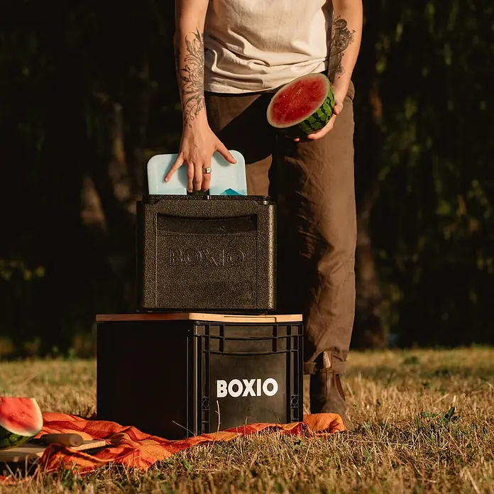 Boxio Kühlbox Cool - Schwarz, 16 l, 1 -tlg. - Schwarze BOXIO Kühlbox wird mit Kühlakku befüllt, gestapelt auf einer BOXIO Kiste, im Freien mit Wassermelone.