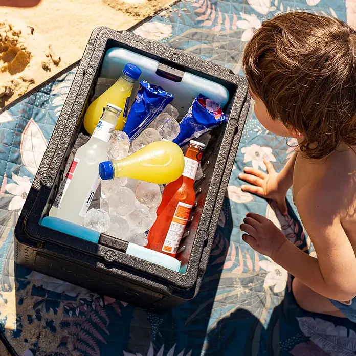 Boxio Kühlbox Cool - Schwarz, 16 l, 1 -tlg. - Offene schwarze Kunststoffkühlbox gefüllt mit Getränken und Eis auf einer Picknickdecke, Kind schaut hinein.