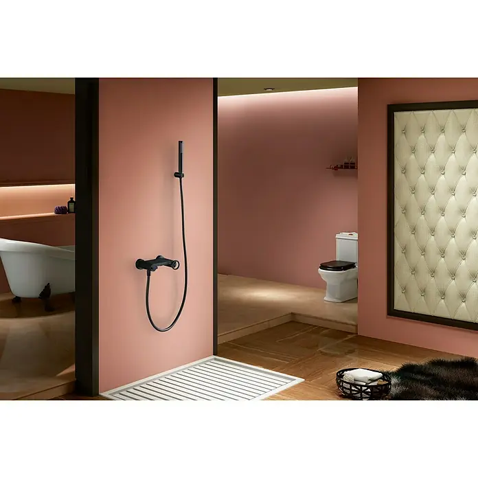 Imex Olimpo Grifo de ducha - Negro - Grifo de ducha negro con ducha de mano y manguera. El grifo de ducha está montado en una pared rosa en un baño moderno.