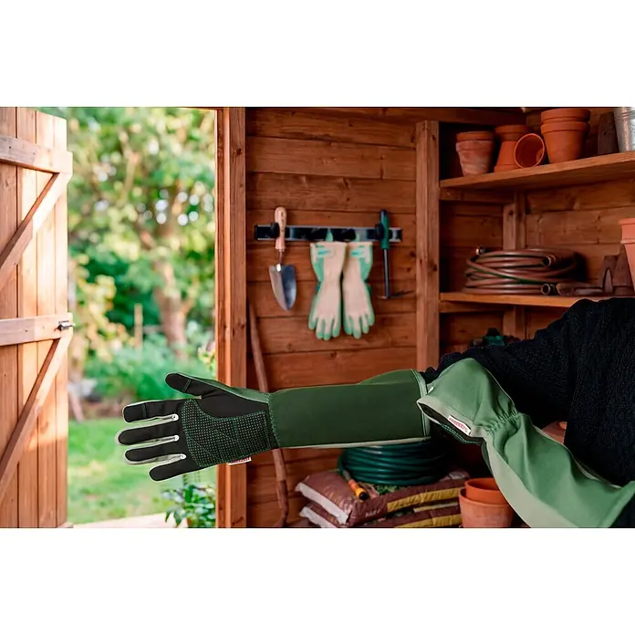 Gardol Gartenhandschuhe mit Stulpen - 8, M, Grün - Person trägt lange grüne Gartenhandschuhe mit verstärkten Handflächen in einem Gartenschuppen.
