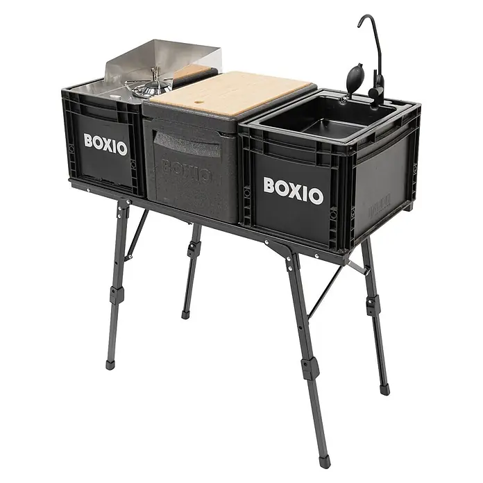 Boxio Campingtisch - L x B x H: 90 x 21 x 11,5 cm, Aluminium - Schwarze modulare Campingküche mit Kochfeld, Kühlbox mit Schneidebrett und Spüle mit Wasserhahn auf einem Klappständer.