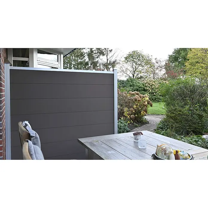 GartenLand Steckzaun-Element WPC Zaun Ameland Ohne Pfosten Ohne Abschlussleiste - B x H: 180 x 180 cm, Anthrazit, Verbundwerkstoff - Dunkelgrauer Sichtschutz mit silbernem Rahmen auf einer Terrasse, bietet Schutz und Privatsphäre zum Garten.