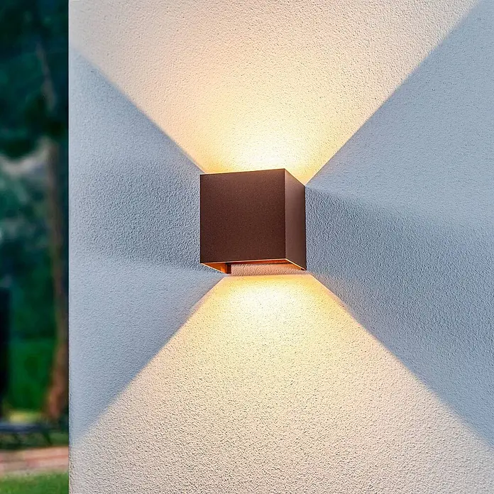 Lindby Außenwandleuchte Nivar - braun / rost, IP54 - Dunkelbraune, würfelförmige Außenwandleuchte an einer strukturierten Wand mit warmem Up- & Downlight.
