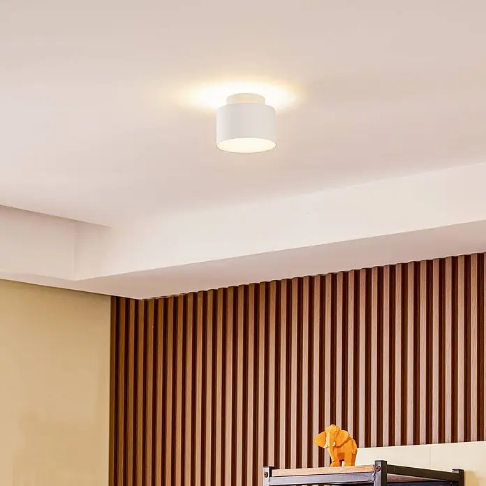 Lindby Deckenstrahler Nivoria - weiß / opal - Weiße zylindrische Deckenleuchte an einer Decke, die warmes, weiches Licht in den Raum abgibt.