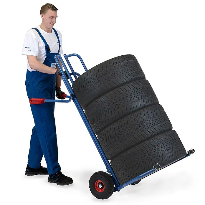 Fetra Sackkarre - Traglast: 200 kg - Blauer Reifenkarren, beladen mit einem Stapel Reifen, von einer Person bedient.