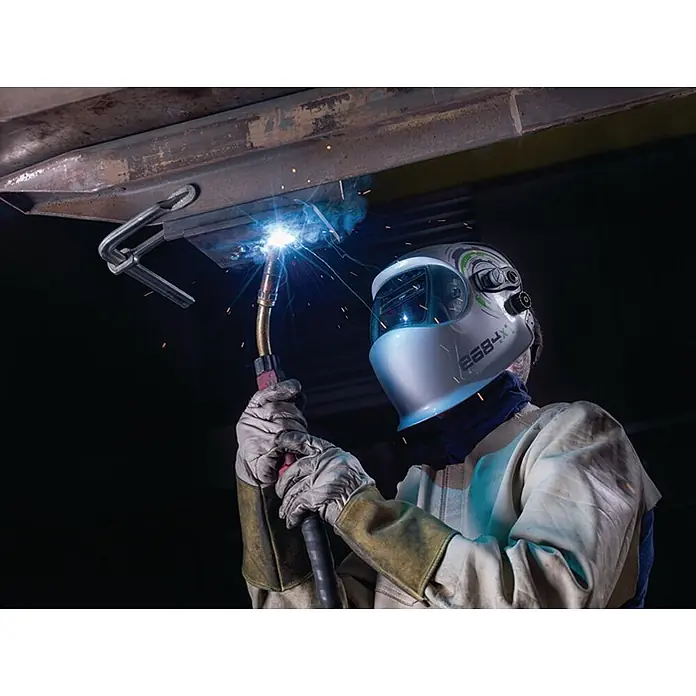 Optrel Schweißhelm E684 -  - Eine Person trägt einen hellgrauen Schweißhelm und Handschuhe beim Schweißen von Metall mit einem Brenner, wodurch helle Funken entstehen.