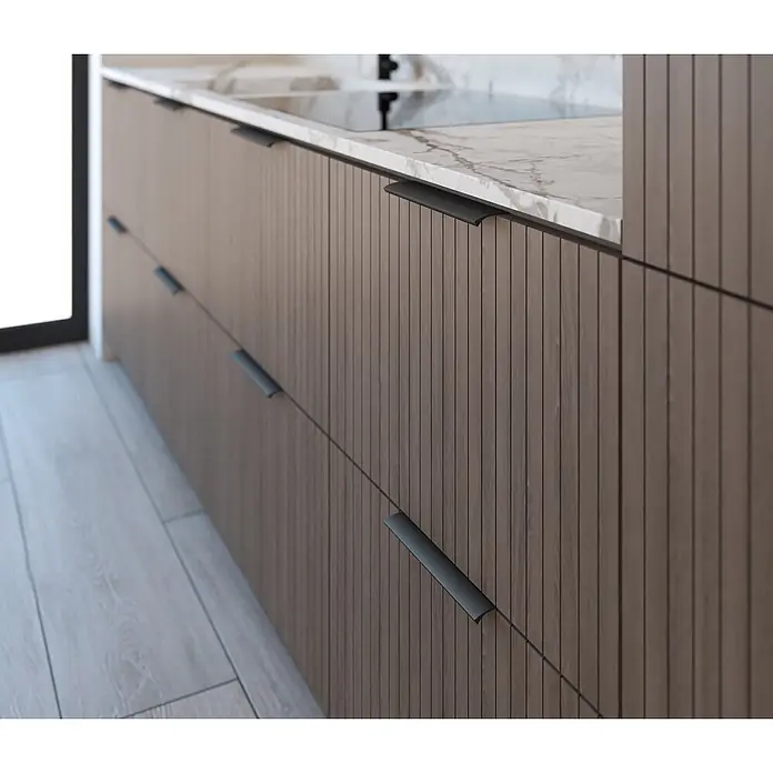 Cordia Möbelgriff 20 cm - Lochabstand: 160 mm, Aluminium, Schwarz - Moderne Küchenschränke mit dunklen geriffelten Holzfronten und eleganten schwarzen Griffen, bedeckt mit einer weißen Marmorplatte.