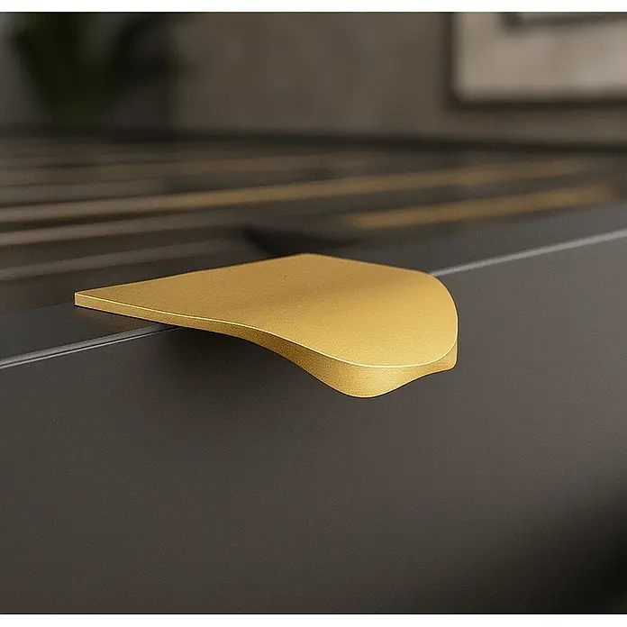 Cordia Möbelgriff 5 cm - Lochabstand: 24 mm, Aluminium, Gold - Gebürsteter goldener, gebogener Griff, der in die Oberkante eines dunkelgrauen Schranks oder einer Schublade integriert ist.