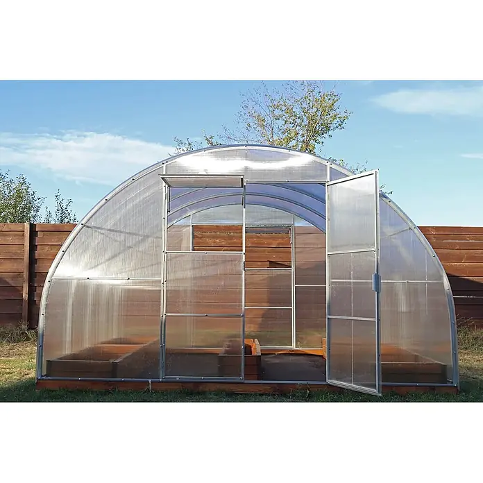 Garten Dream Gewächshaus Majestic, 4mm Polycarbonat - Außenmaß inkl. Dachüberstand (B x T): 400 x 400 cm, Material Seitenwand: Kunststoff, 4 mm, Silber - Gewölbtes Polycarbonat-Gewächshaus mit offener Tür und erhöhten Holzbeeten innen, im Garten vor einem Holzzaun.