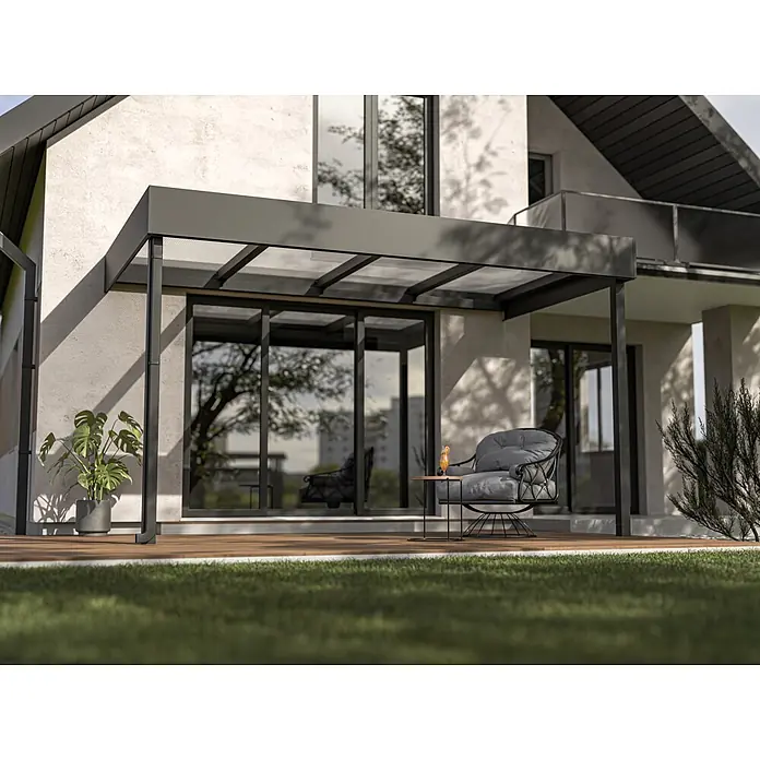 Terrassenüberdachung nach Maß - Stahl, Konfigurierbar - Dunkelgraue Pergola mit transparentem Dach an modernem Haus, beschattet Holzterrasse mit Sessel.