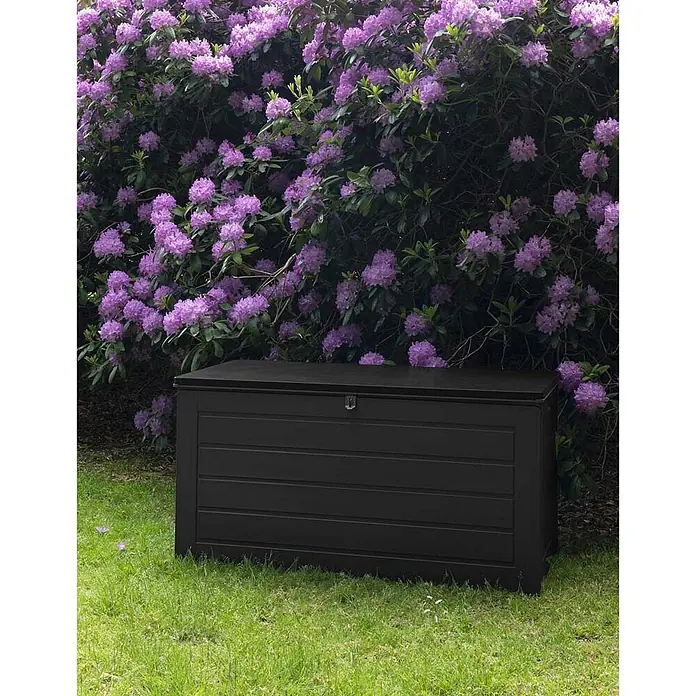 Ebuy24 Garten-Aufbewahrungsbox Dubrovnik - L x B x H: 61 x 147 x 65 cm, Schwarz, Kunststoff - Schwarze Gartenaufbewahrungsbox mit Paneel-Design auf Gras in einer Gartenumgebung.