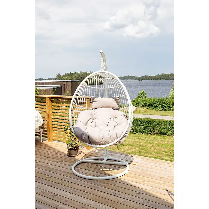 Ebuy24 Hängesessel Viga - Polyester, Weiß - Weißer Outdoor-Hängesessel mit beigen Kissen auf einer Holzterrasse mit Seeblick.