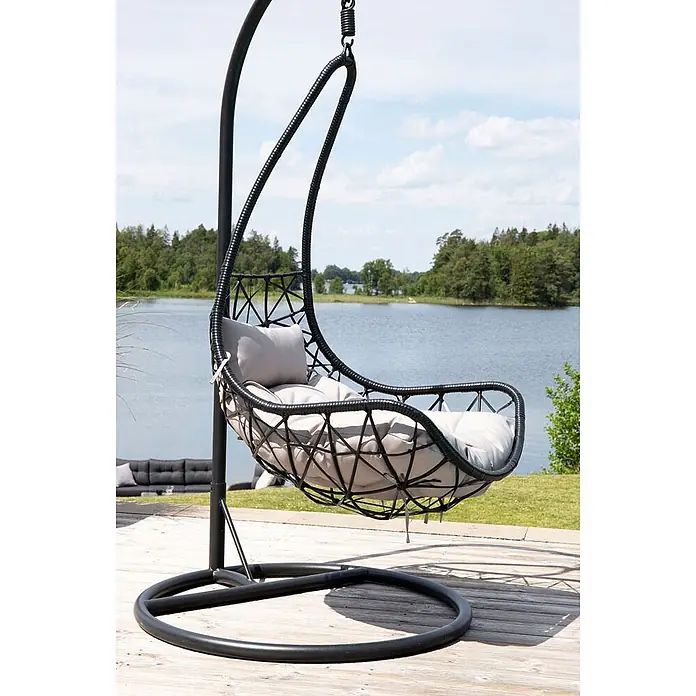 Ebuy24 Hängesessel Vide - Polyester, Schwarz - Schwarzer Rattan-Hängesessel mit hellgrauen Kissen auf einer Terrasse am See.
