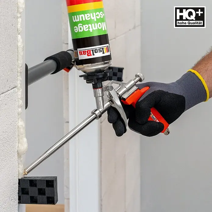 IsolBau Bauschaum 1 x Montageschaum 750 ml, PU-Reiniger 500 ml, Schaumpistole - 750 ml - Hand trägt Montageschaum aus einer Dose mit Metall-Schaumpistole und orangem Griff in eine Wandfuge auf.