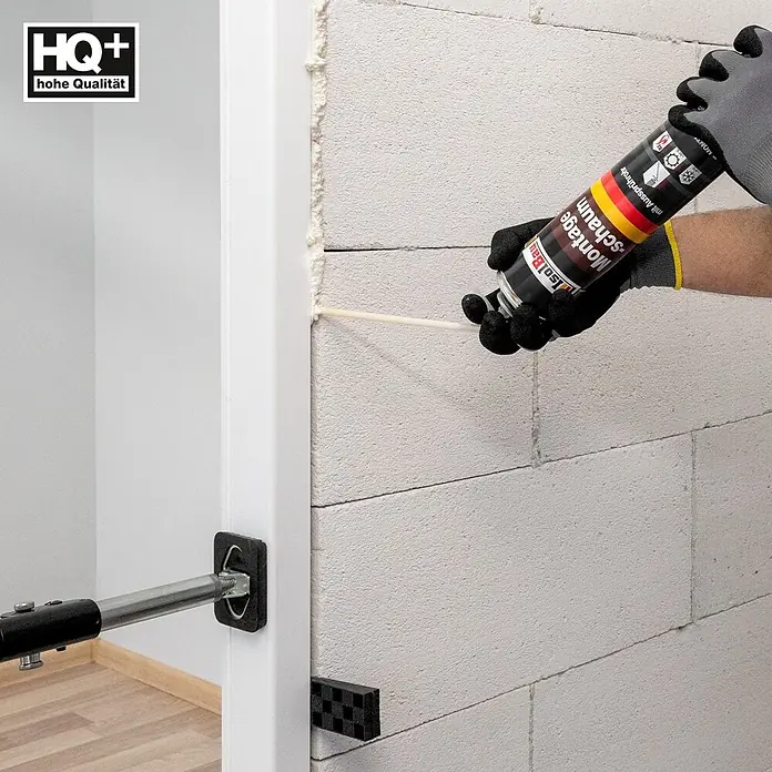 IsolBau Adapterschaum Montageschaum mit Aussprührohr 1 x 750 ml - 750 ml - Anbringen von Montageschaum zum Abdichten eines weißen Türrahmens, fixiert mit einer Türspreize, an einer Blockwand.