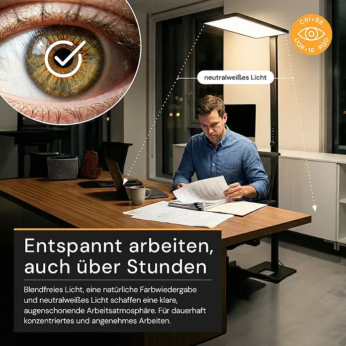 Enovalite LED-Stehleuchte - 150 W, Höhe: 199 cm, Schwarz, Neutralweiß - Hohe, schwarze Stehleuchte beleuchtet einen Arbeitsplatz, an dem ein Mann arbeitet. Sie spendet neutralweißes, blendfreies Licht für Augenschonung.