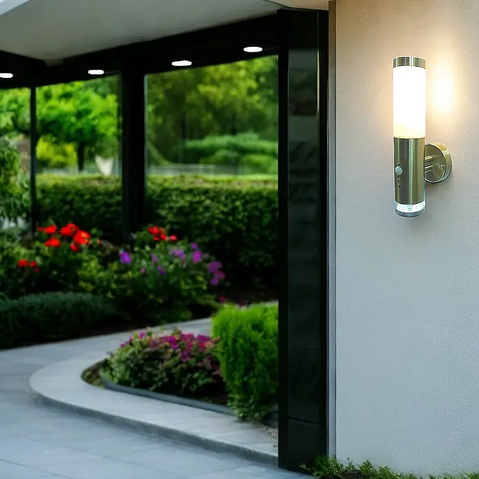 DAPO Außenwandleuchte Lisa, mit LED-Kranz, Edelstahl, E27, IP44 -  - Silberne Außenwandleuchte mit weißem Diffusor und Bewegungssensor, beleuchtet eine Terrasse.