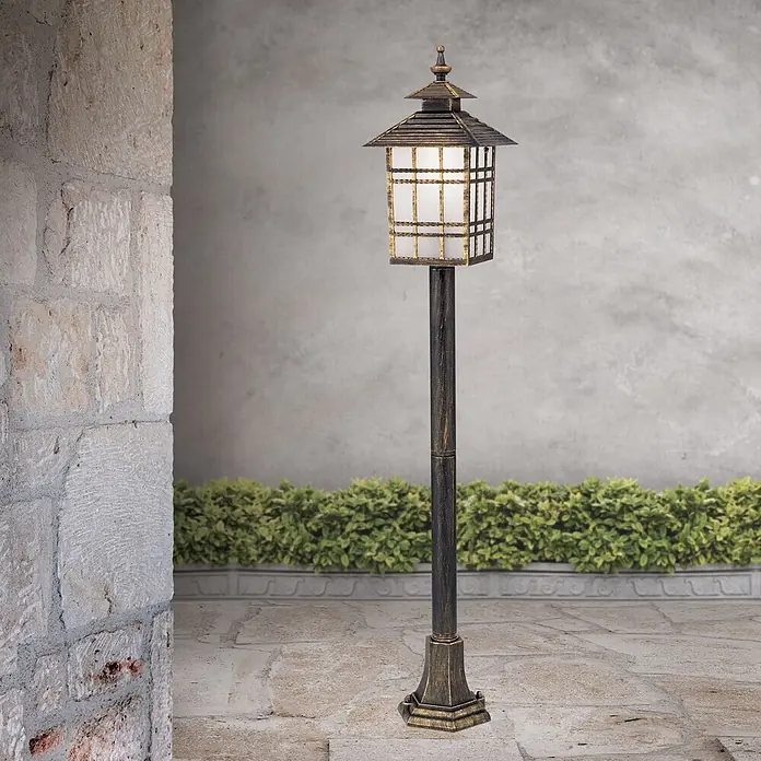 Orion Leuchten Außenlaterne Kiko - 60 W, Farbe Gehäuse: Bronze, Ohne Leuchtmittel - Hohe Außenstandleuchte in Bronze-Gold-Optik mit japanischem Laternenkopf und Milchglasscheiben auf gepflasterter Terrasse.