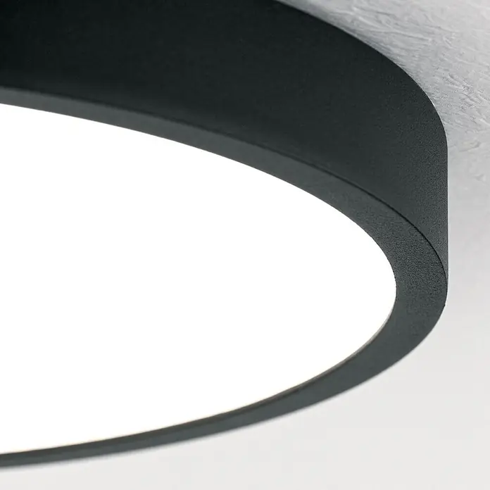 Orion Leuchten LED-Panel rund -  - Nahaufnahme einer runden, schwarzen, strukturierten LED-Leuchte, die hellweißes Licht abstrahlt.