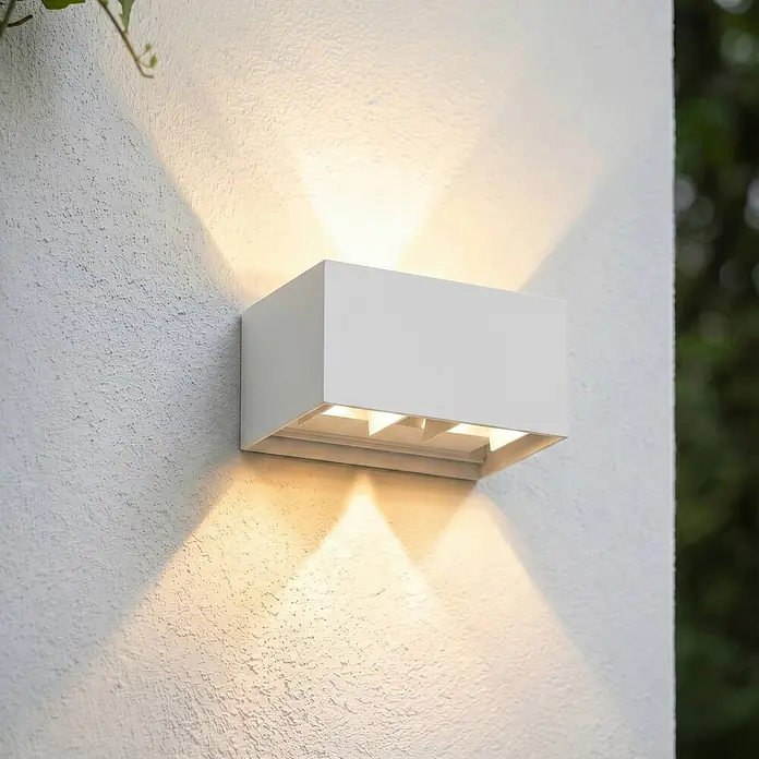 Lindby Außenwandleuchte Nivar - weiß / opal, weiß / opal, IP54 - Eine rechteckige weiße Außenwandleuchte an einer strukturierten weißen Wand, die warmes Licht nach oben und unten wirft.
