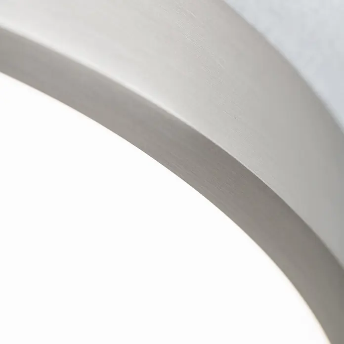 Orion Leuchten LED-Panel rund -  - Nahaufnahme einer gebogenen Leuchte aus gebürstetem Silber, die weißes Licht ausstrahlt.