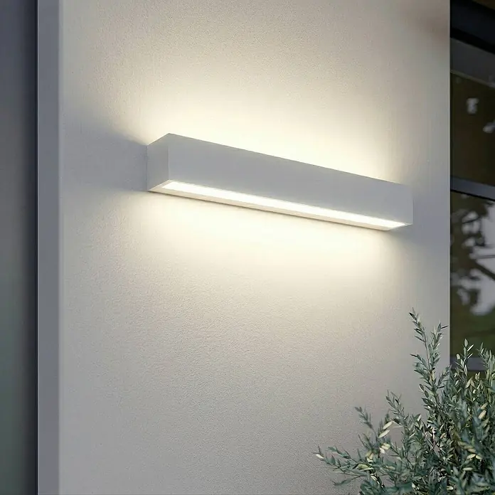 Lucande Außenwandleuchte Lengo - weiß / opal, IP65 - Weiße rechteckige Außenwandleuchte, die warmes Licht auf eine strukturierte Wand wirft.