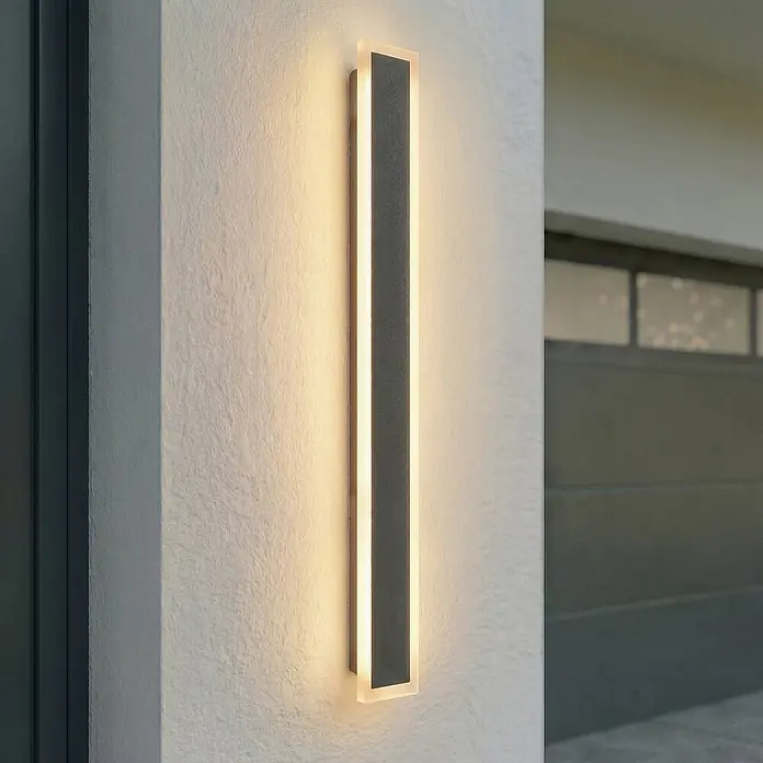 Lucande LED Wandleuchte aussen in schwarz, Aussenlampe Wand -  - Moderne, rechteckige Außenwandleuchte in Dunkelgrau mit beleuchteten Seiten, vertikal an einer strukturierten Wand montiert.