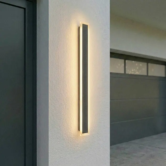 Lucande LED Wandleuchte aussen in schwarz, Aussenlampe Wand -  - Vertikale dunkelgraue Außenwandleuchte mit beleuchteten Seitenstreifen, montiert an einer strukturierten Außenwand.