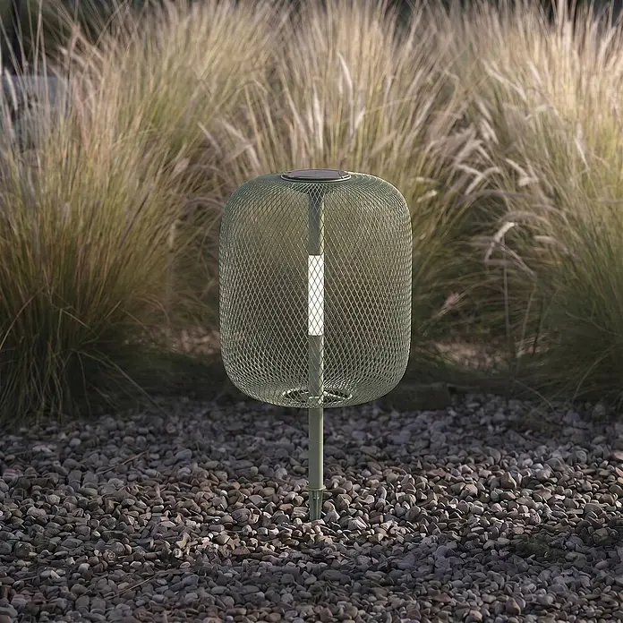 Lucande LED Solar Gartenlampe Erdspieß in grün, dimmbar Erdspießlampe -  - Grüne Gitter-Solar-Gartenleuchte, leuchtend, in Kies zwischen hohem Gras gesteckt.