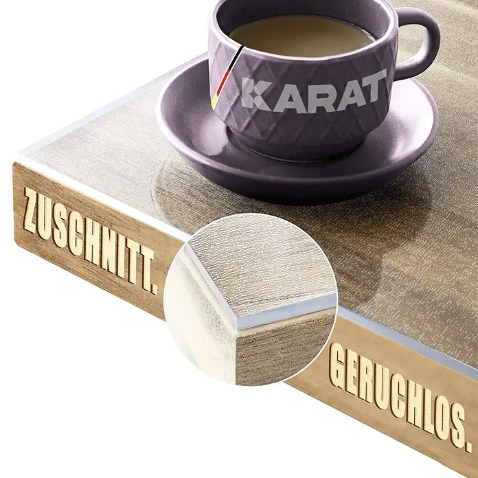 Karat Tischbelag Gerade Kante - 100 x 60 cm, Transparent, Kunststoff - Hölzernes Schneidebrett mit transparenter, strukturierter Oberflächenschicht und den Beschriftungen 'ZUSCHNITT.' und 'GERUCHLOS.', Detailansicht der Kante.