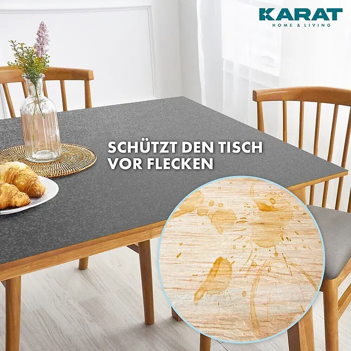 Karat Tischbelag Schräge Kante - 140 x 80 cm, Dunkelgrau, Kunststoff - Dunkelgrauer, strukturierter Tischschutz auf einem Holztisch, schützt vor Flecken. Detail zeigt eine fleckige Holzoberfläche.