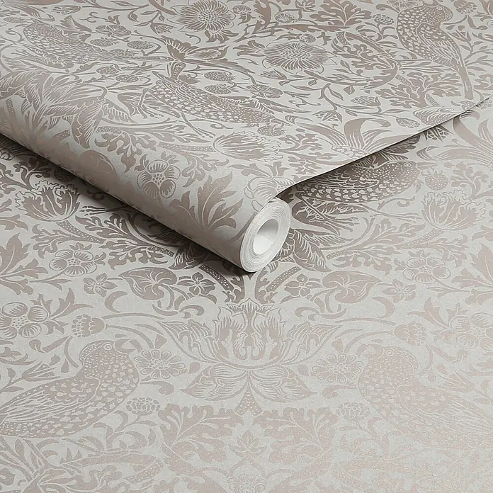 William Morris At Home Vliestapete Erdbeerdieb - Beige, Floral, 1.000 x 52 cm - Teilweise abgerollte Tapetenrolle mit einem dezenten hellbeigen und taupefarbenen Muster aus Vögeln, Blumen und Blättern.