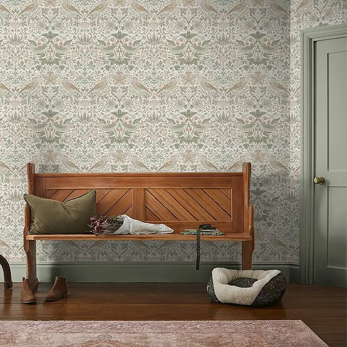 William Morris At Home Vliestapete Vliestapete Erdbeerdieb - Salbeigrün, Floral - Verspielte Tapete mit Blumen- und Vogelmuster in sanften Grün- und Rosatönen, schmückt einen gemütlichen Eingangsbereich mit Holzbank.