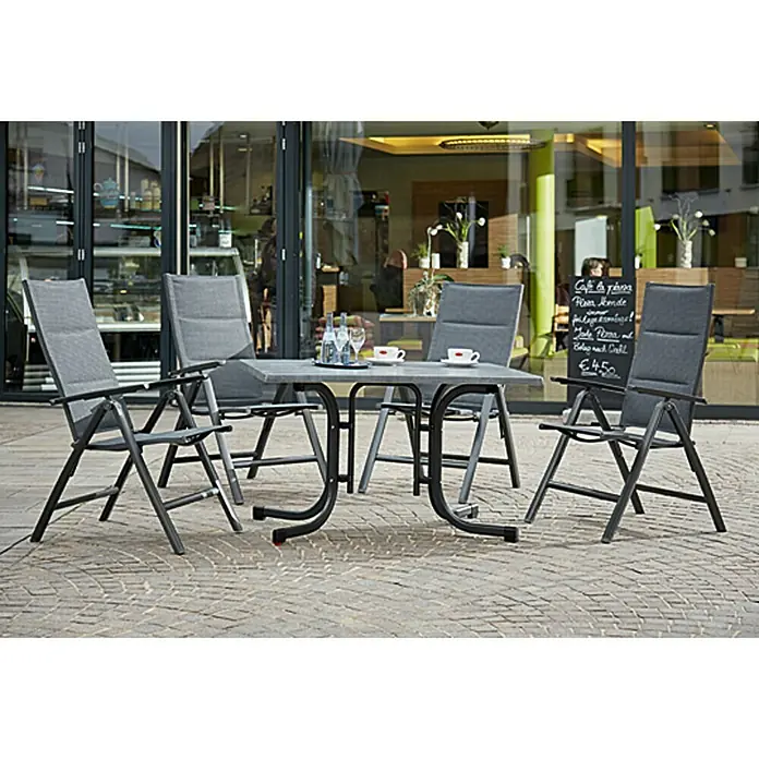 Sunfun Maja Garten-Positionssessel - Anthrazit, Klappbar - Graue Gartentischgruppe mit vier Stühlen vor einem Café. Die Möbel sind modern und wetterfest für den Außenbereich.