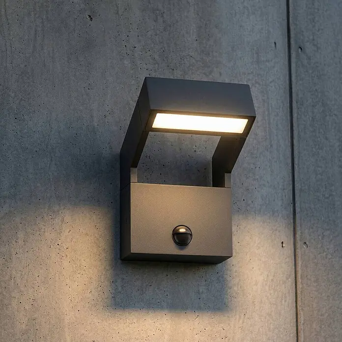 Arcchio Außenwandleuchte Kovato - alu / grau / zink, IP65 - Anthrazitfarbene LED-Außenwandleuchte mit Bewegungssensor, die nach oben und unten auf eine Betonwand strahlt.