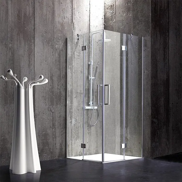 Kiamami Valentina Eckdusche - 70 x 70 x 190 cm, Transparent, Stärke: 6 mm - Klarglas-Eckdusche mit weißer Duschwanne und Armaturen, neben einem modernen weißen Garderobenständer in einem Betonbad.