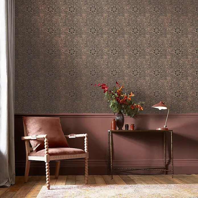 William Morris At Home Vliestapete Vliestapete Ringelblume, faserig - Kupfer/Schwarz, Floral, 10 x 0,52 m - Detailreiche Blumentapete mit Blattmuster in dunklen Bronze- und Kupfertönen an einer Wohnzimmerwand.