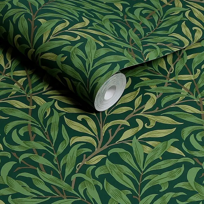 William Morris At Home Vliestapete Weidenzweig - Grün, Floral, 1.000 x 52 cm - Teilweise abgerollte Rolle dunkelgrüner Tapete mit naturinspiriertem Blattmuster.
