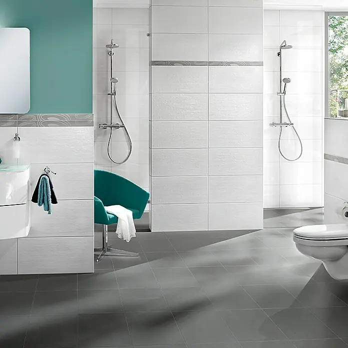 Wandfliese Eifel New - 30 x 60 cm, Weiß, Matt - Badezimmer mit weißen Fliesen, grauen Bodenfliesen, einer Toilette und einem grünen Sessel. Elegantes Design mit moderner Ausstattung für Komfort.