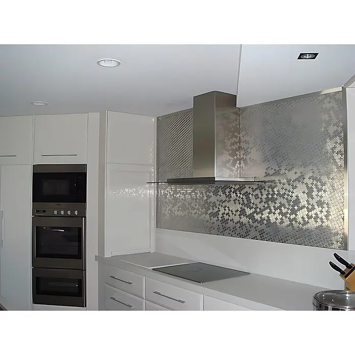 ALLOY Mosaikfliese Mosaik Fliese massiv Edelstahl hochglanz grau 1,6mm Swiss Cross-S-S-M - 322 x 322 mm, Grau, Silber, Hochglänzend - Moderne weiße Küche mit Edelstahlgeräten, schwarzem Induktionskochfeld und metallisch gemusterter Spritzschutzwand.