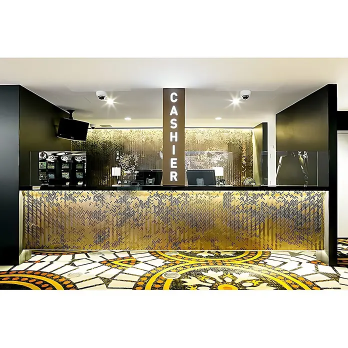 ALLOY Mosaikfliese Mosaik Fliese massiv Titan gebürstet gold 1,6mm stark Herringbone-Ti-GB - 309 x 300 mm, Gold, Sonstiges - Kassenbereich mit goldfarbener Texturfront, schwarzer Theke und vertikalem „CASHIER“-Schild, ausgestattet mit Monitoren und Kameras.