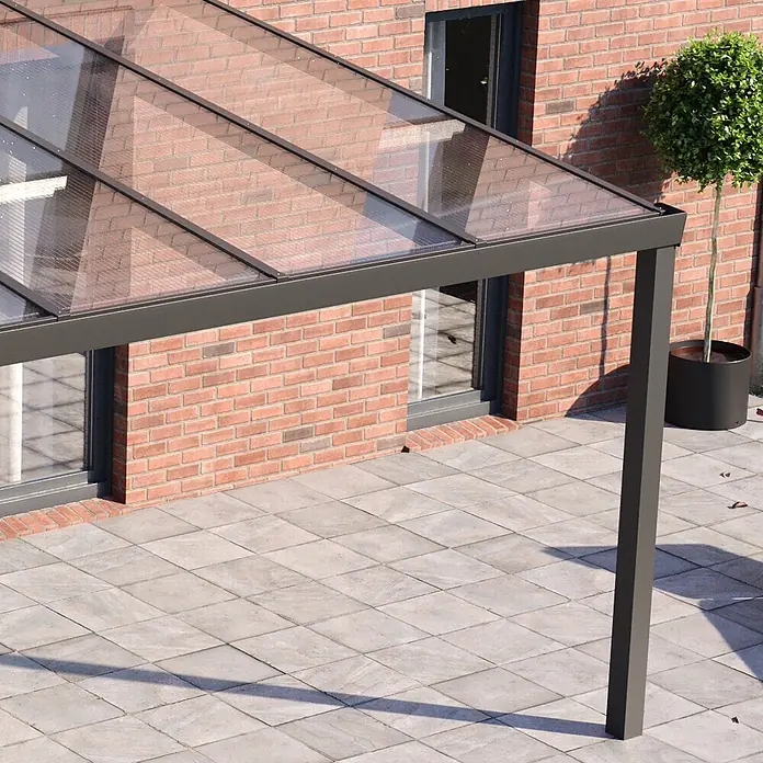 Exolon Stegplatte S5X 16/25 - L x B x S: 4.000 x 980 x 16 mm, Polycarbonat, Transparent - Dunkelgraues Metall- und Transparentpanel-Terrassendach an Backsteinhaus über gefliester Terrasse.