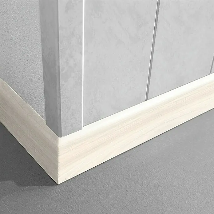 LOGOCLIC Sockelleiste K 58 Buche Donau - 260 cm x 10 mm x 58 mm, MDF - Ein detailliertes Foto zeigt eine Sockelleiste mit Holzmaserung in einem Raum mit grauem Boden und hellgrauen Wänden, die einen sauberen Übergang bildet.