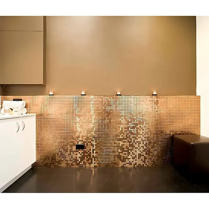 ALLOY Mosaikfliese Mosaik Fliese massiv Titan gebürstet kupfer 1,6mm stark Mosaic-Ti-AB - 322 x 322 mm, Bronze, Sonstiges - Dekorative Wand aus schimmernden kupferfarbenen Quadratfliesen in einem modernen Raum, mit weißer Ablage und dunklen Sitzgelegenheiten.