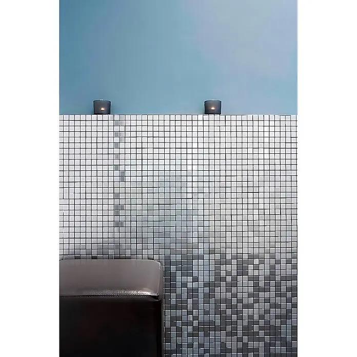 ALLOY Mosaikfliese Mosaik Fliese massiv Edelstahl marine gebürstet grau 1,6mm Mosaic-S-S-MB - 322 x 322 mm, Grau, Silber, Blau, Sonstiges - Wand mit schimmernden quadratischen Mosaikfliesen, die von hellem Silber zu Dunkelgrau übergehen. Eine dunkle Polsterbank steht im Vordergrund.