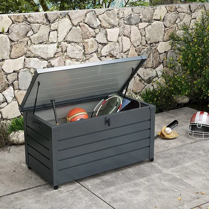 Outsunny Garten-Aufbewahrungsbox - Dunkelgrau, Stahl - Dunkelgraue Outdoor-Aufbewahrungsbox mit geöffnetem Deckel, der Sportgeräte zeigt. Steht auf einer Terrasse vor einer Steinmauer.