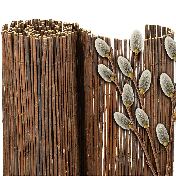 NOOR Sichtschutzelement DELUXE Weidematte - Naturmaterialien, Natur - Gerollter Natur-Reisigzaun, teilweise abgerollt, mit dekorativen Weidenkätzchenzweigen.